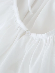 Detailed close-up of white gathered neckline with a classic four-hole decorative button