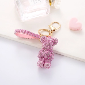 Close-up of pink rhinestone bear keychain with matching leather strap and gold hardware