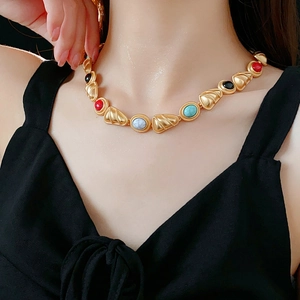 Detail of vintage gold necklace with colorful beads worn by a model on a black top
