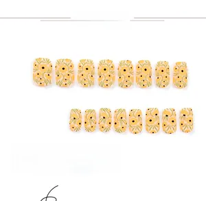 Detail of short floral press-on nails with yellow flower patterns and matte bicolor design