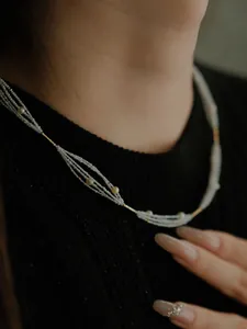 Close-up of multi-layer pearl and gold bead necklace draped on a black knit top