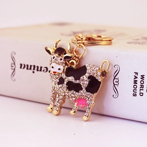 Cute cow keychain with sparkling crystals and black enamel on a gold metal frame