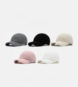 Detail view of knitted baseball caps in grey, black, cream, pink, and white ribbed fabric