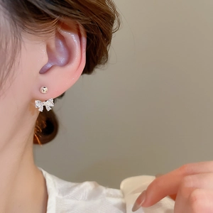 Close-up of sparkling zircon bow earrings with s925 silver needle on model ear