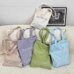 Detail view of large canvas tote bags in five pastel colors with minimalist typography