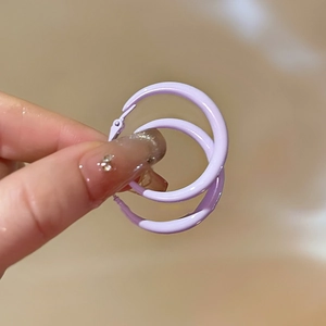 Close-up of hand holding purple minimalist round hoop earrings with glossy finish