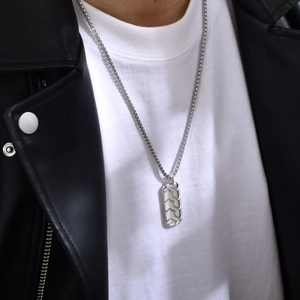Detail of male model wearing silver stainless steel rectangle necklace with tire pattern