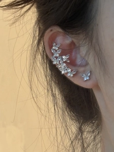 Close-up of silver butterfly ear cuffs with sparkling zircons worn on ear