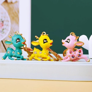 Detail of rhinestone-encrusted cartoon deer keychains in blue, yellow, and pink metal