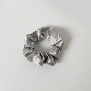 Detailed view of a silver grey satin scrunchie featuring smooth silk-like texture and folds