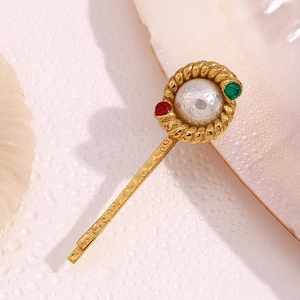 Detailed macro of gold plated twist hair clip with center pearl and colorful gemstones