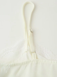 Detail of adjustable strap and delicate lace trim on white satin camisole top