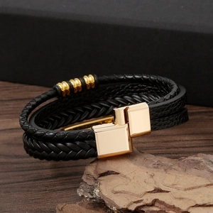 Detail of multi-layer black braided leather bracelet with golden magnetic clasp