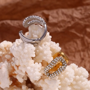 Dettaglio macro di ear cuff in oro e argento con cristalli incastonati su corallo