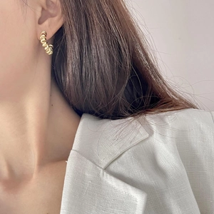 Minimalist twisted spiral earrings in gold finish worn by model in white suit