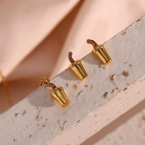 Macro shot of gold soda cup jewelry featuring pink crystals on marble and pink fabric