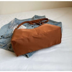 Detailed side view of brown nylon tote bag showing wide base and adjustable strap