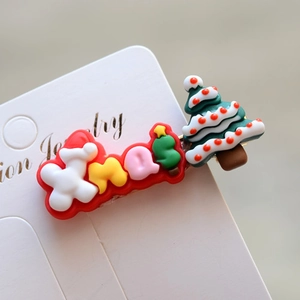 Detailed view of a green Christmas tree hair clip with colorful Xmas letter embellishments