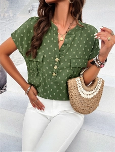 Detailed close-up of green polka dot V-neck blouse with buttons and high quality fabric