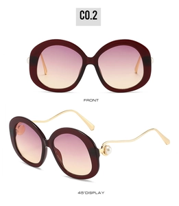 Detail of round burgundy oversized sunglasses with gold temples and pearl accents