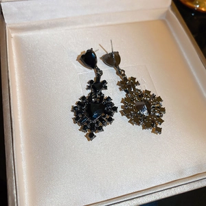 Detailed view of black gothic heart earrings with crystals in a jewelry box