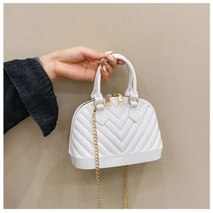 Detail of white shell-shaped jelly bag with V-textured surface and golden metal chain