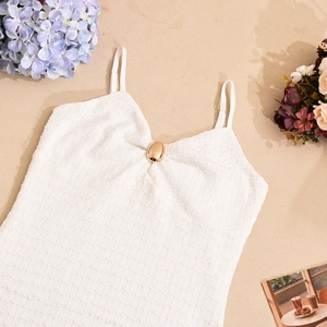 Détail de la texture gaufre de la robe blanche à bretelles avec boucle dorée chic