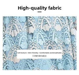 Detailed macro view of light blue water-soluble lace fabric with white embroidery