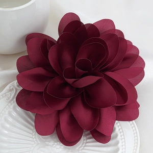 Macro detail of dark wine red floral fabric brooch with multilayered petals on white decor