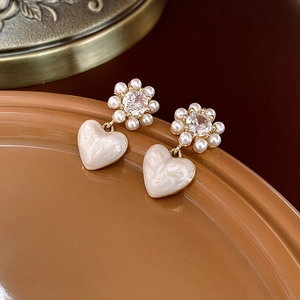 Vintage heart pearl drop earrings with gold floral studs on a ceramic tray display