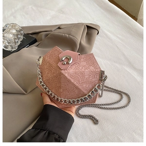 Close-up of pink geometric handbag with lace texture and silver chain strap