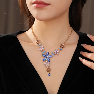 Détail d'un collier vintage doré orné de fleurs en cristal bleu et violet avec pampilles