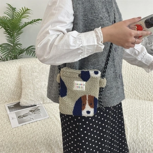Detail of plush crossbody bag featuring cute cartoon dog patterns and fabric logo tag