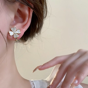 Detail of gold bow earrings with pearls and zircon in a clover-inspired design