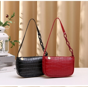 Detail of crocodile pattern texture on two hobo underarm bags in black and red colors