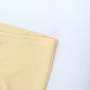 Detailed close-up of double-needle stitching on light yellow fabric dress hem
