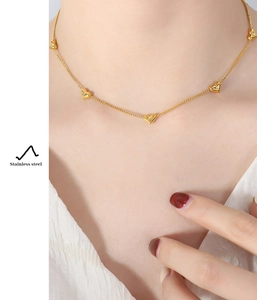 Close-up of model wearing heart pendant necklace in polished gold stainless steel