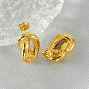 Detail of twisted gold titanium steel earrings on elegant satin with glass decor
