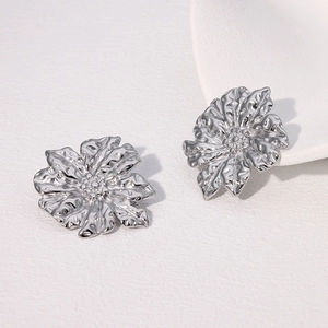 Macro shot of silver petal earrings with hammered metal texture and layered floral details