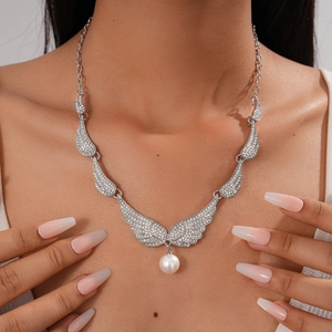Close-up of model wearing a sparkling angel wing pendant necklace with a white pearl drop