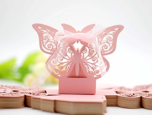 Close-up of pink laser-cut butterfly candy box with ribbon and unassembled flat cards