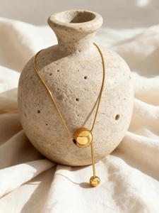 Détail du collier chaîne serpent en acier inoxydable doré 18 carats sur vase