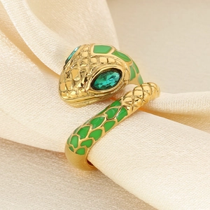 Snake shaped gold ring with emerald eyes on silk background, luxury fashion jewelry
