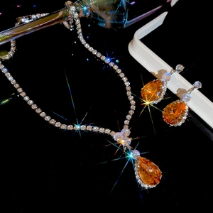 Macro shot of silver jewelry set with shimmering orange teardrop gemstones on black backdrop