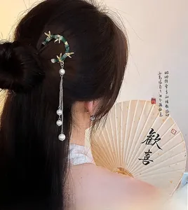 Détail de l'épingle à cheveux bambou vert avec feuilles dorées et pompons en perles