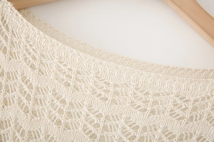 Detail of cream crochet knit top showing round neck and intricate hollow out patterns