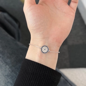 Makroaufnahme von Silberarmband mit blauem Zirkon-Teufelsauge am Handgelenk