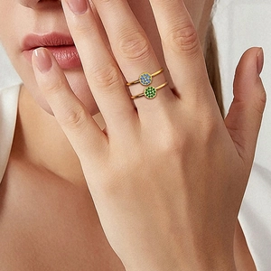 Detailed view of two gold stackable rings featuring blue and green gemstone clusters
