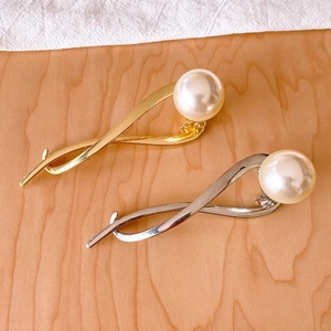 Minimalist alloy hair claw clips in gold and silver with large pearl accents on wood background
