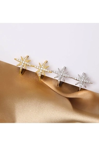 Detail of star-shaped zircon ear cuffs in gold and silver finish on silk fabric